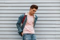 Fashion model good-looking young man in stylish pink sweatshirt in fashionable blue denim jacket with fabric shopper near vintage Royalty Free Stock Photo