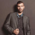 Fashion model handsome stylish man in suit on gray wall background. Elegant fashionable beautiful brutal man