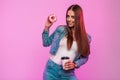 Fashion model happy young woman with cute smile in trendy blue denim jacket with tea with donut in sweet glaze posing near pink Royalty Free Stock Photo