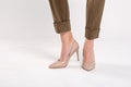 Fashion model in khaki pants and beige high heels on white background