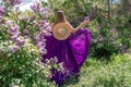 Fashion Model in Lilac Flowers, Young Woman in Beautiful Long Dress Waving on Wind, Outdoor Beauty Portrait in Blooming