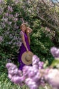 Fashion Model in Lilac Flowers, Young Woman in Beautiful Long Dress Waving on Wind, Outdoor Beauty Portrait in Blooming Royalty Free Stock Photo