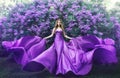 Fashion Model in Lilac Flowers, Young Woman in Beautiful Long Dress Waving on Wind, Outdoor Beauty Portrait in Blooming Garden