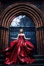 Fashion Model near Medieval Castle Gate Door, Woman Beauty Glamour Portrait in Elegant Red Dress Royalty Free Stock Photo