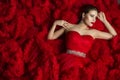 Fashion Model on Red Background, Beautiful Woman Posing on Wavy Fabric Background Royalty Free Stock Photo