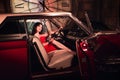 Fashion model in red dress in a retro car invites you to come in