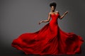 Fashion Model in Red Long waving Luxury Dress. Dark Skinned Beauty Woman with Afro Black Hairstyle dancing over Gray Background.