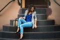 Fashion Model In Street. Beautiful Sexy Woman In Stylish Fashionable Fall Clothes sitting on stairs Royalty Free Stock Photo