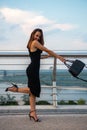 Fashion model wearing black elegant dress posing outdoor at river Dniper bank in Kyiv, Ukraine. Young beautiful brunette caucasian Royalty Free Stock Photo