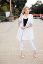 Fashion model in white jacket on stairs on street. Royalty Free Stock Photo