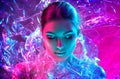 Fashion model woman in colorful bright neon lights posing in studio through transparent film. Portrait of beautiful sexy girl Royalty Free Stock Photo