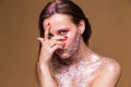 Fashion model woman with trendy glitter make-up look through the fingers