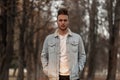 Fashion model of a young man in fashionable youth clothes with a trendy hairstyle in the forest among the trees. European guy Royalty Free Stock Photo