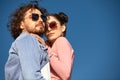 Fashion models couple wearing sunglasses. Sexy woman and handsome young man portrait over light background. Attractive Royalty Free Stock Photo