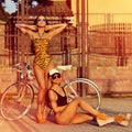 Fashion models in swimsuits posing outdoors near a vintage bike