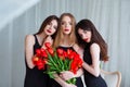 Fashion models in tender black dresses posing in sensual way at luxury interior full of tulips. Young woman sensuality.