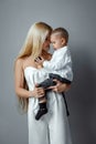 Fashion mom in a white elegant outfit and a baby on a gray background. Feminism concept, mother`s day
