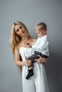 Fashion mom in a white elegant outfit and a baby on a gray background. Feminism concept, mother`s day