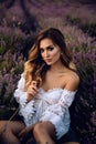 Beautiful girl with blond hair in elegant clothes posing in summer flowering lavender field