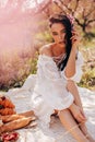 Beautiful sensual woman with dark hair in elegant dress posing among flowering peach trees Royalty Free Stock Photo