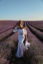 Sexy woman with blond hair in elegant clothes with accessories posing in blooming lavender fields