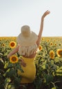 Beautiful woman with blond hair in elegant dress posing in flowering sunflower field Royalty Free Stock Photo