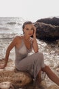 Beautiful woman with dark hair in elegant beach dress posing on sunset beach Royalty Free Stock Photo