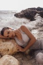 Beautiful woman with dark hair in elegant beach dress posing on sunset beach Royalty Free Stock Photo