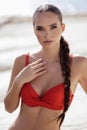 beautiful woman with dark hair in elegant red swimming suit posing in the white stones beach in Cyprus