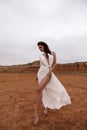 beautiful woman with dark hair in luxurious white dress with accessories posing in desert in Cyprus Royalty Free Stock Photo