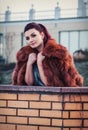 Fashion outdoor photo of glamour woman with dark hair wearing luxurious fur coat and leather gloves Royalty Free Stock Photo