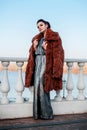 Fashion outdoor photo of glamour woman with dark hair wearing luxurious fur coat and leather gloves Royalty Free Stock Photo