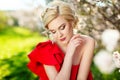 Fashion, people and summer holidays concept - beautiful woman red dress sunbathing over green blooming garden background Royalty Free Stock Photo
