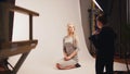 Fashion photo backstage - Blonde handsome girl posing for photographer - model sits at knees Royalty Free Stock Photo