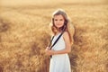 Fashion photo of a little girl in white dress and straw hat at the evening wheat field Royalty Free Stock Photo