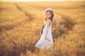 Fashion photo of a little girl in white dress and straw hat at the evening wheat field Royalty Free Stock Photo