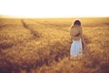 Fashion photo of a little girl in white dress and straw hat at the evening wheat field Royalty Free Stock Photo