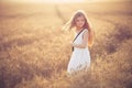 Fashion photo of a little girl in white dress and straw hat at the evening wheat field Royalty Free Stock Photo