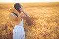 Fashion photo of a little girl in white dress and straw hat at the evening wheat field Royalty Free Stock Photo