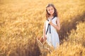 Fashion photo of a little girl in white dress and straw hat at the evening wheat field Royalty Free Stock Photo