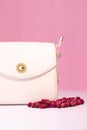 fashion photo of purse. white woman handbag near little roses flowers. isolated on white and pink background. Product Royalty Free Stock Photo