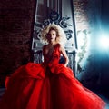 Fashion photo of young magnificent woman. Running towards camera. Seductive blonde in red dress with fluffy skirt Royalty Free Stock Photo