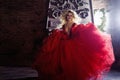 Fashion photo of young magnificent woman. Running towards camera. Seductive blonde in red dress with fluffy skirt Royalty Free Stock Photo