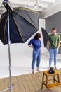 Fashion photography in a photo studio. Professional male photographer taking pictures of beautiful woman model on camera, Royalty Free Stock Photo