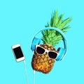 Fashion pineapple sunglasses and headphones listens to music on smartphone