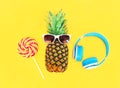 Fashion pineapple with sunglasses lollipop caramel and headphones over colorful yellow