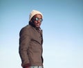 Fashion portrait african man listens to music in winter over blue sky