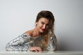 Fashion portrait of a beautiful smiling woman with long hair in a pretty silver dress with tinsel sitting at the table Royalty Free Stock Photo