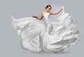 Fashion portrait of a beautiful woman in a waving white dress. Light fabric flies in the wind