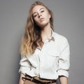 Fashion portrait of a beautiful young blonde woman in a white shirt in the studio on a gray background Royalty Free Stock Photo